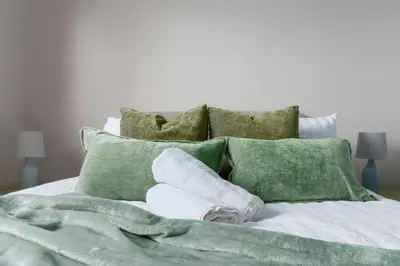 a bed with green pillows and towels on it at The Cozy Atmosphere Lodge in Moffat