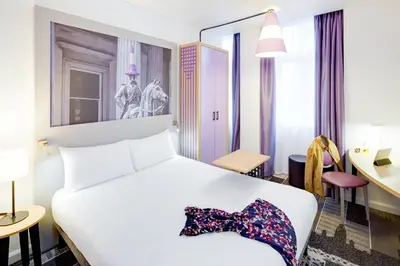 a bedroom with a white bed with a bow tie on it at ibis Styles Glasgow Centre George Square in Glasgow