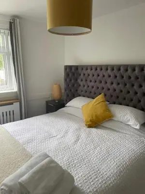 a bedroom with a large bed with a yellow pillow at Modern flat in quiet residential cul-de-sac in Kilwinning