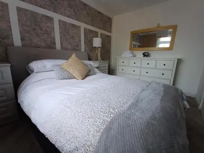 a bedroom with a white bed with a mirror and a dresser at Modern flat in quiet residential cul-de-sac in Kilwinning
