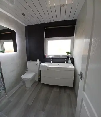 a bathroom with a sink and a toilet and a window at Modern flat in quiet residential cul-de-sac in Kilwinning