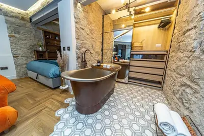 a bathroom with a large tub and a bedroom at Canon Cave in Edinburgh