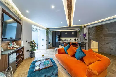 a living room with an orange couch and a kitchen at Canon Cave in Edinburgh