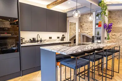 a kitchen with a large island with blue bar stools at Canon Cave in Edinburgh