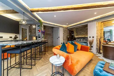 an open kitchen and living room with an orange couch at Canon Cave in Edinburgh