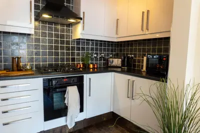 a kitchen with white cabinets and black tiles at Grassmarket Old Town Boutique Apartment in Edinburgh