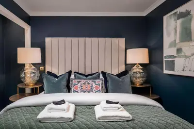 a bedroom with a large bed with blue walls and two lamps at Sapphire Suite, The Stirling Residence in Stirling