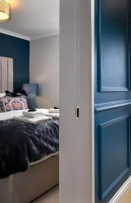 a bedroom with a bed with blue walls and a door at Sapphire Suite, The Stirling Residence in Stirling