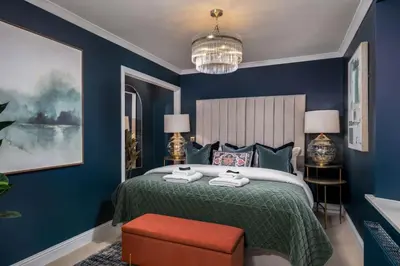 a blue bedroom with a bed and a red stool at Sapphire Suite, The Stirling Residence in Stirling