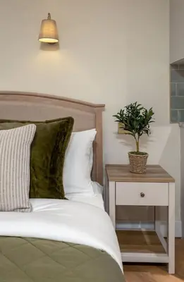 a bedroom with a bed and a nightstand with a plant at Bridgend Studio - Near Free Parking in Stirling