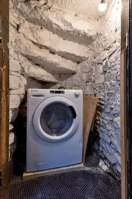 a washer and dryer in a room with a stone wall at Bridgend Studio - Near Free Parking in Stirling