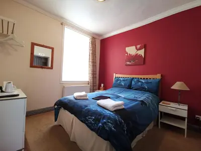 a bedroom with a blue bed and a red wall at Summer's Bay in Rothesay
