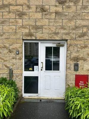 a white door on a brick building with plants at Modern Apt commute to Edinburgh in Livingston