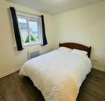 a bedroom with a white bed with a window at Modern Apt commute to Edinburgh in Livingston