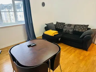 a living room with a black couch and a table at Modern Apt commute to Edinburgh in Livingston