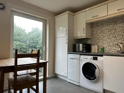 a kitchen with a washing machine and a table and a window at 2 Bed & 2 Bath-Flat-Driving Distance to Edinburgh in Uphall