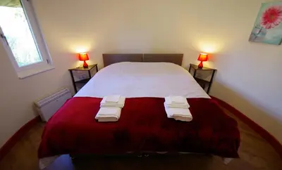 a bedroom with a red and white bed with two lamps at Fun holiday lodges in historic walled garden near Falkirk, Heart of Scotland Holidays in Falkirk