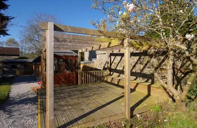a wooden deck with a gate and a tree at Fun holiday lodges in historic walled garden near Falkirk, Heart of Scotland Holidays in Falkirk