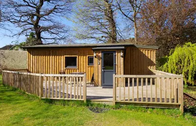 a wooden shed with a gate and a door at Fun holiday lodges in historic walled garden near Falkirk, Heart of Scotland Holidays in Falkirk
