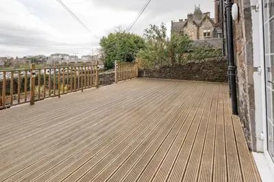 a wooden deck with a fence and a building at Stirling Townhouse Apartment Btm in Stirling