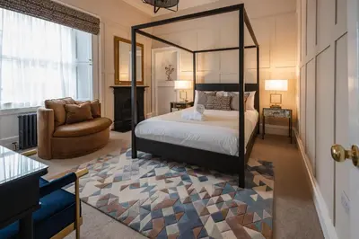 a bedroom with a canopy bed and a chair at Stirling Townhouse Apartment Top in Stirling