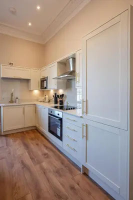 a kitchen with white cabinets and a large door at Stirling Townhouse Apartment Top in Stirling