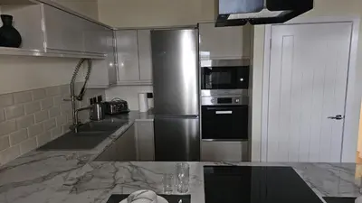 a kitchen with a stainless steel refrigerator and a sink at Harbour Havens Apartments in Moffat