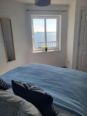 a bedroom with a blue bed and a window at Harbour Point -Coorie Doon Stays in Saltcoats