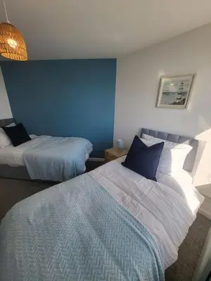 a bedroom with two beds and a blue wall at Harbour Point -Coorie Doon Stays in Saltcoats