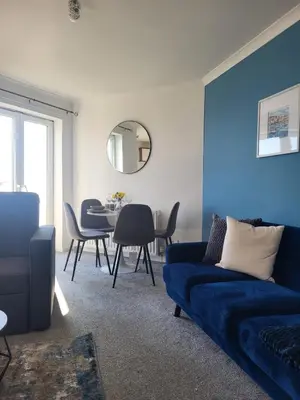 a living room with a blue couch and a table at Harbour Point -Coorie Doon Stays in Saltcoats