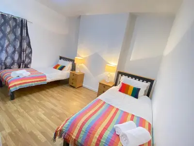 two twin beds in a room with wooden floors at Luxurious 3 rooms greater London in Moffat