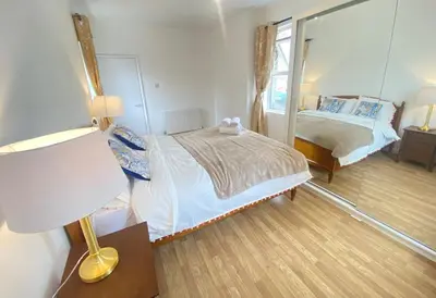 a bedroom with a bed and a mirror and a lamp at Luxurious 3 rooms greater London in Moffat