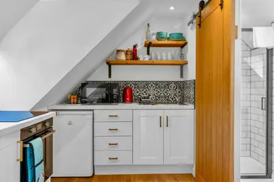 a small kitchen with white cabinets and a staircase at Edinburgh's Springtime Chalet in Roslin