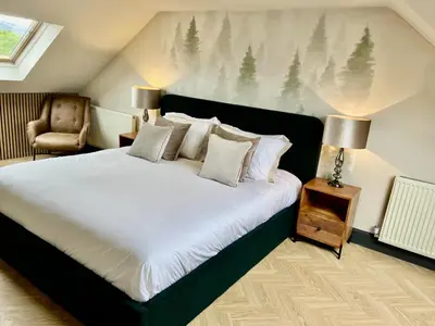 a bedroom with a large bed and a chair at Fergus in ApartNest Auchterarder in Auchterarder