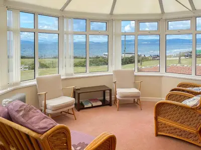 a room with chairs and a bed and windows at Dunrigh Cottage in Blackwaterfoot