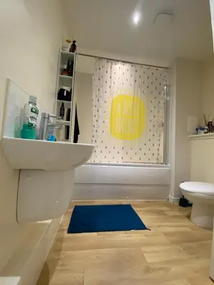 a bathroom with a sink and a toilet and a blue rug at Cosy Room with Shared Bathroom in Edinburgh