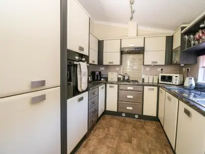 a large kitchen with white cabinets and appliances at RoseGrace Lodge in Auchterarder
