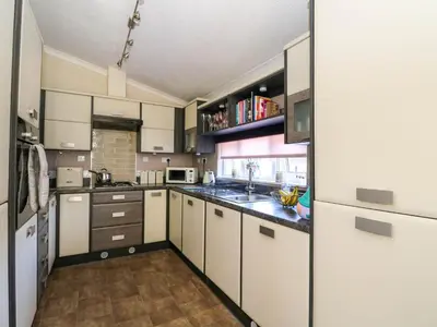 a kitchen with white cabinets and a sink at RoseGrace Lodge in Auchterarder