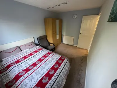 a bedroom with a bed and a chair in it at Cosy two bedroom flat in Glasgow