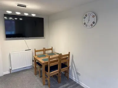 a dining room with a table and a clock on the wall at Cosy two bedroom flat in Glasgow