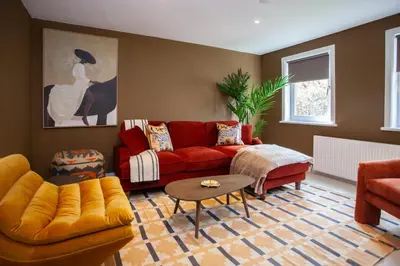 a living room with a red couch and a table at Newly Renovated House in Popular Location in Glasgow