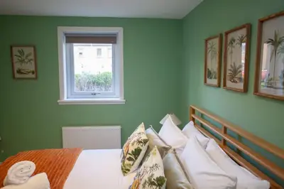 a green bedroom with a bed with a window at Newly Renovated House in Popular Location in Glasgow