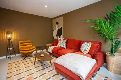 a living room with a red couch and a chair at Newly Renovated House in Popular Location in Glasgow