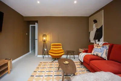 a living room with a red couch and a chair at Newly Renovated House in Popular Location in Glasgow