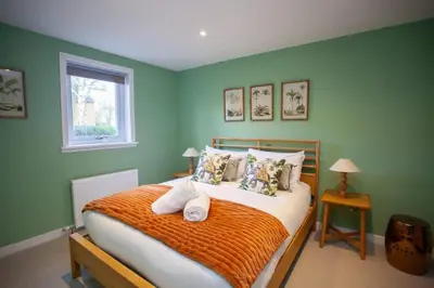 a bedroom with green walls and a bed with pillows at Newly Renovated House in Popular Location in Glasgow