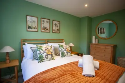 a bedroom with a large bed with green walls at Newly Renovated House in Popular Location in Glasgow