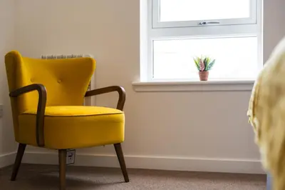 a yellow chair sitting in front of a window at Macallan Apartment in Oban