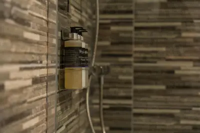 a bathroom with a shower with a bottle of hair products at Macallan Apartment in Oban
