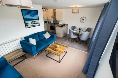 a living room with a blue couch and a table at Macallan Apartment in Oban