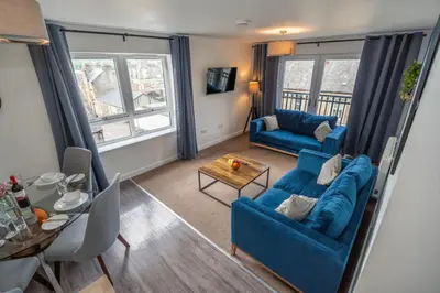 a living room with two blue couches and a table at Macallan Apartment in Oban